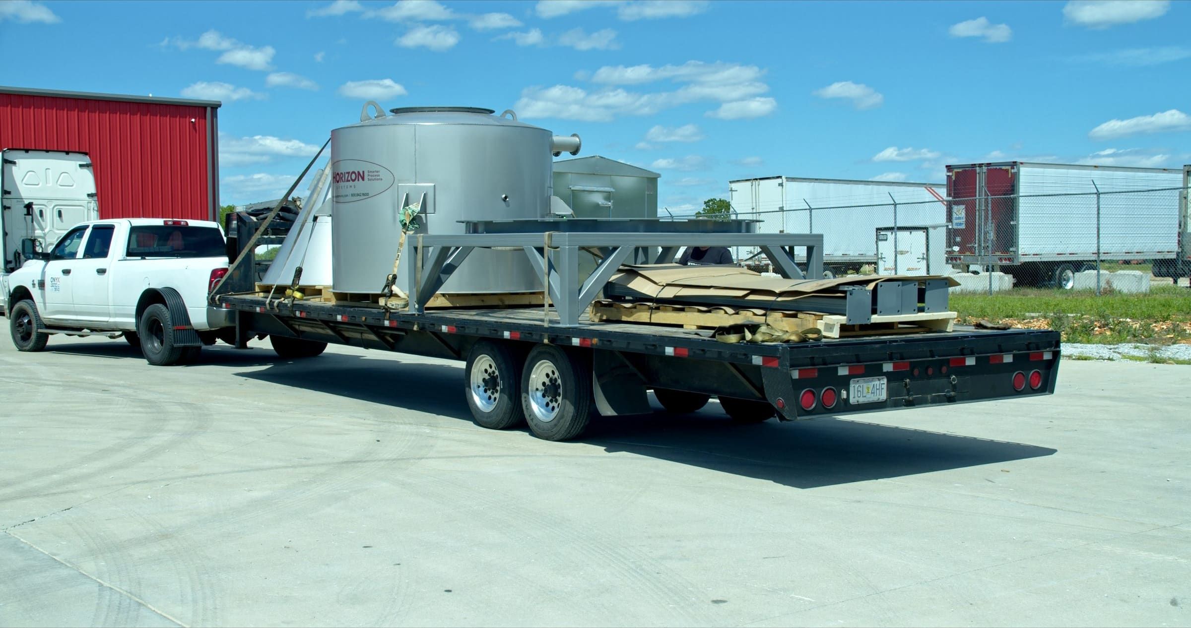 A tarped flatbed load secured on an Onyx Logistics trailer